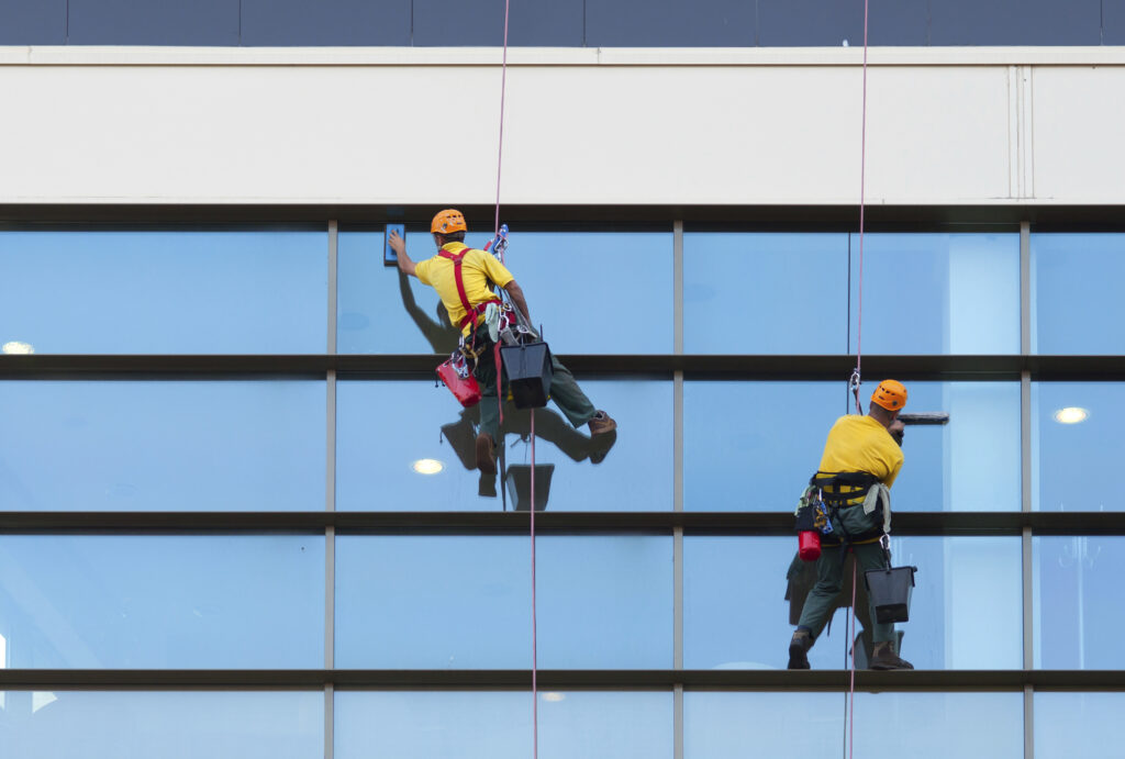 Nettoyage de vitres en hauteur par des agents spécialisés sur la façade d'un bâtiment professionnel.